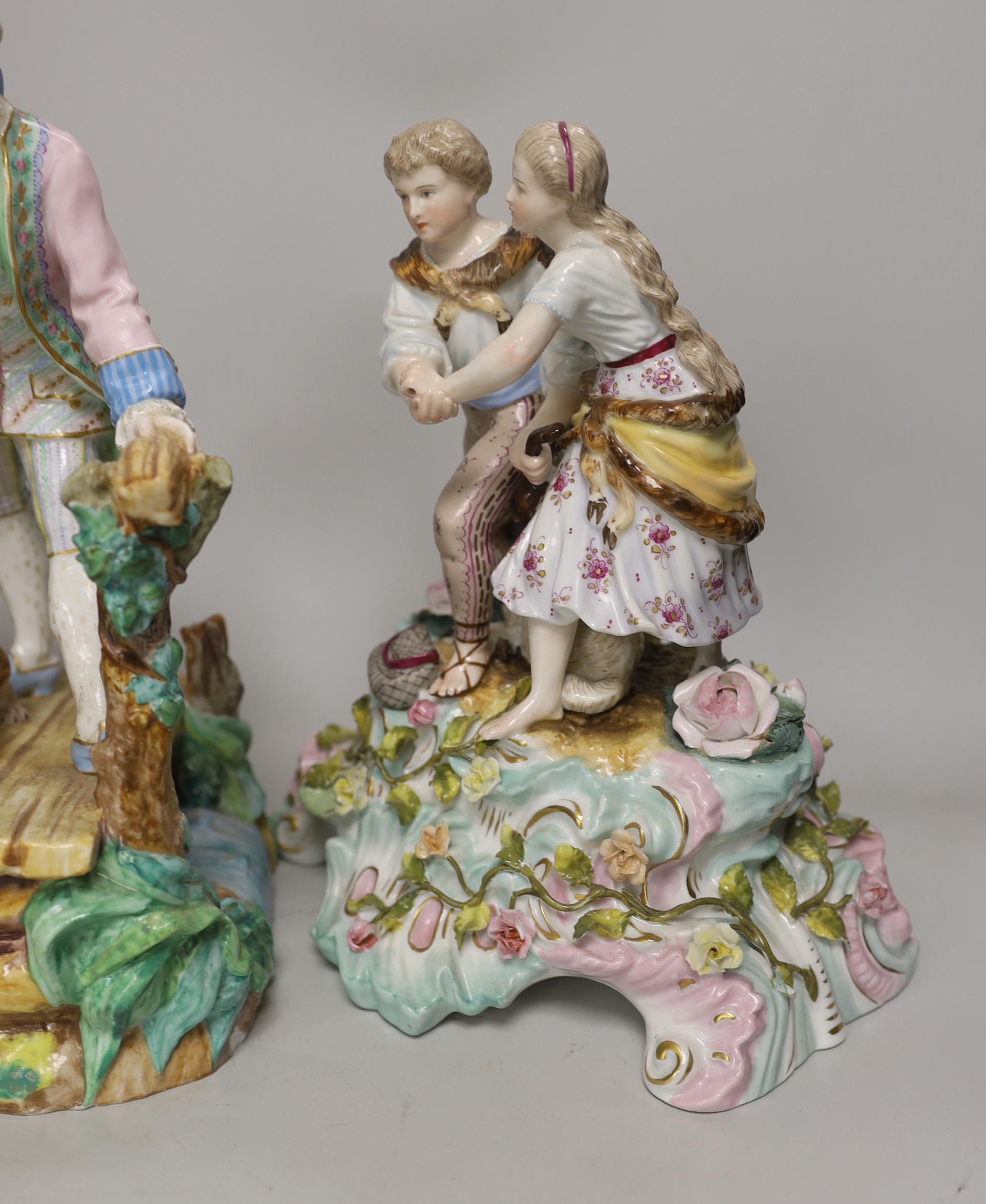 Three German porcelain figures including a Sitzendorf group of a young couple and a sheep, together with a pair of lovers with dogs, highest 28cm